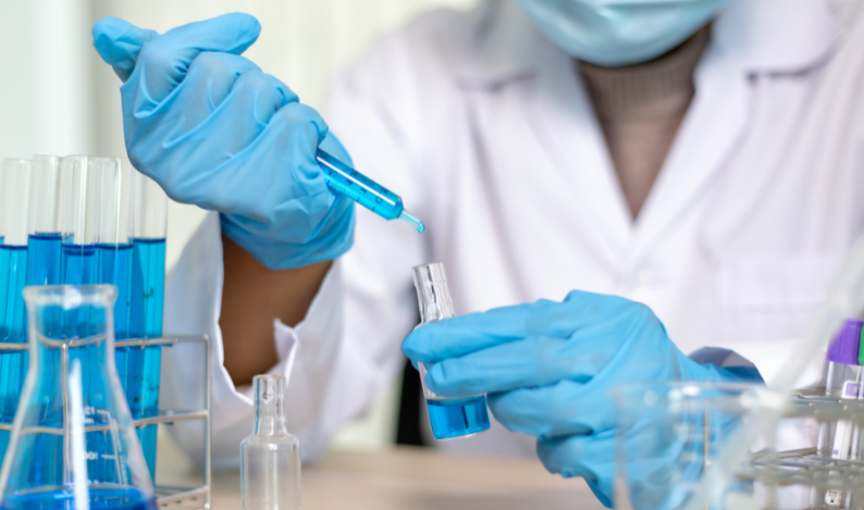 Scientist putting a blue liquid in a test tube glass